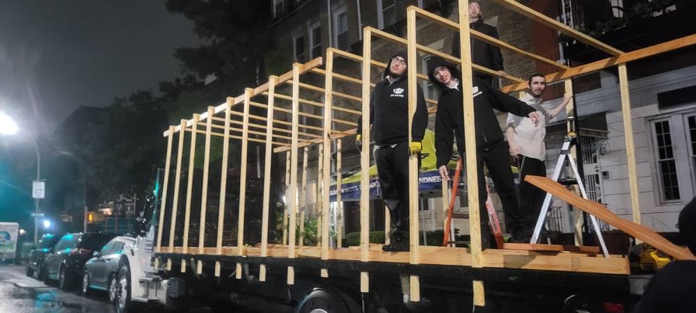 El armazón de madera de una sucá sobre un camión, de noche